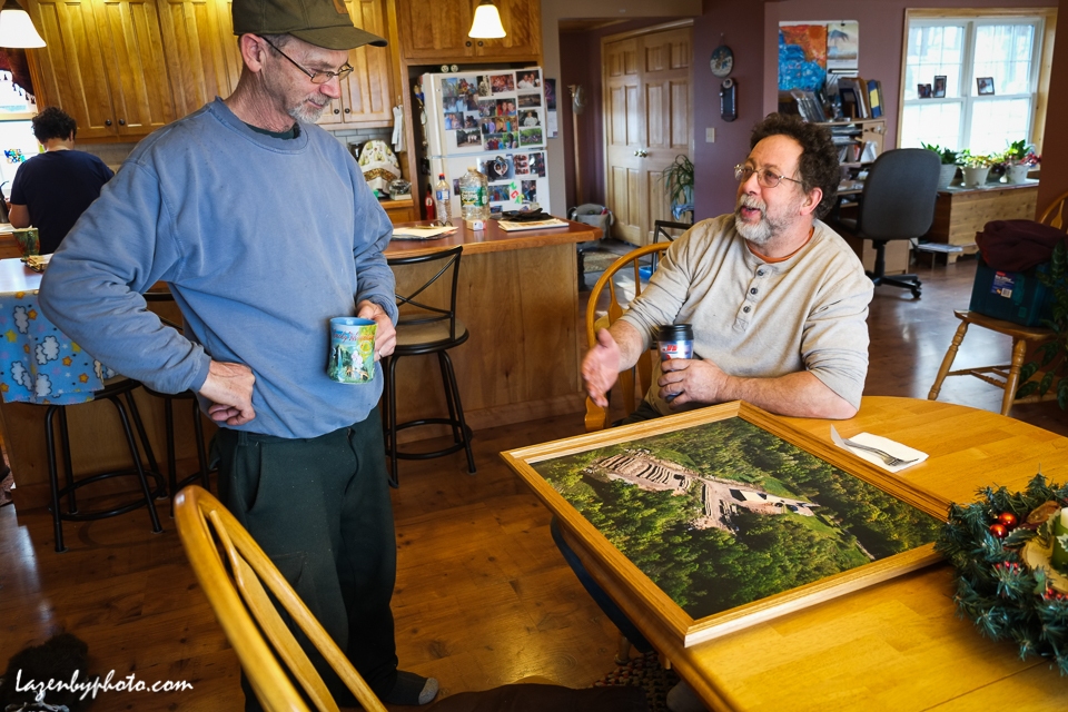 Roger Chaloux, left, and Hector Chaloux in Roger's house with an aerial photo of their wood yard when it was full of wood.
